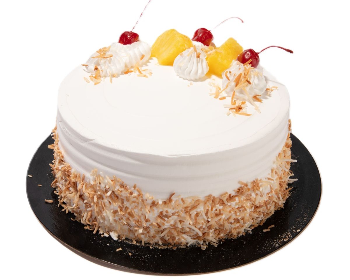 Pina colada cake with white frosting, toasted coconut sides, pineapple chunks, whipped cream, and cherries on top.